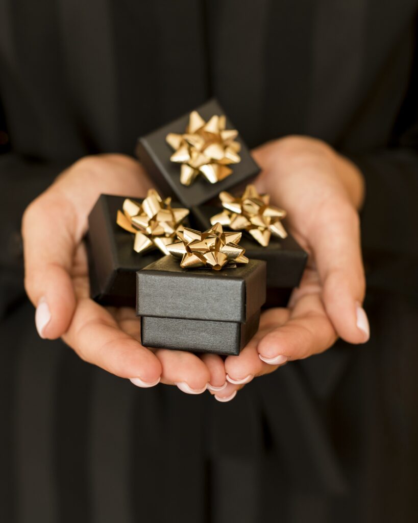 luxurious 4 black custom favor boxes with a golden start design on a top holding by a two hands for a corporate event.