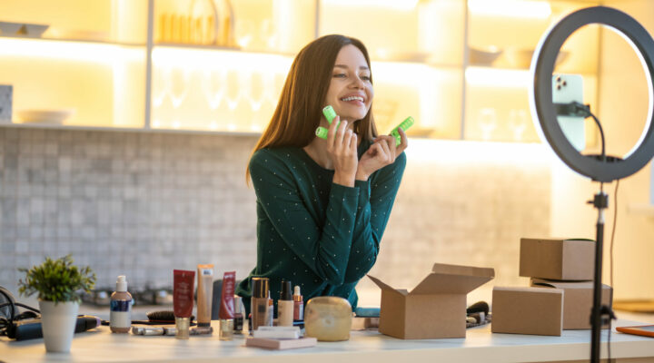An influencer wearing a green color t-shirt presenting cosmetics sent to her in custom PR boxes