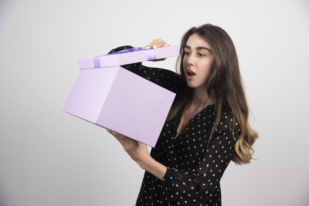 Young woman looking on a purple core custom mystery box on a white background.