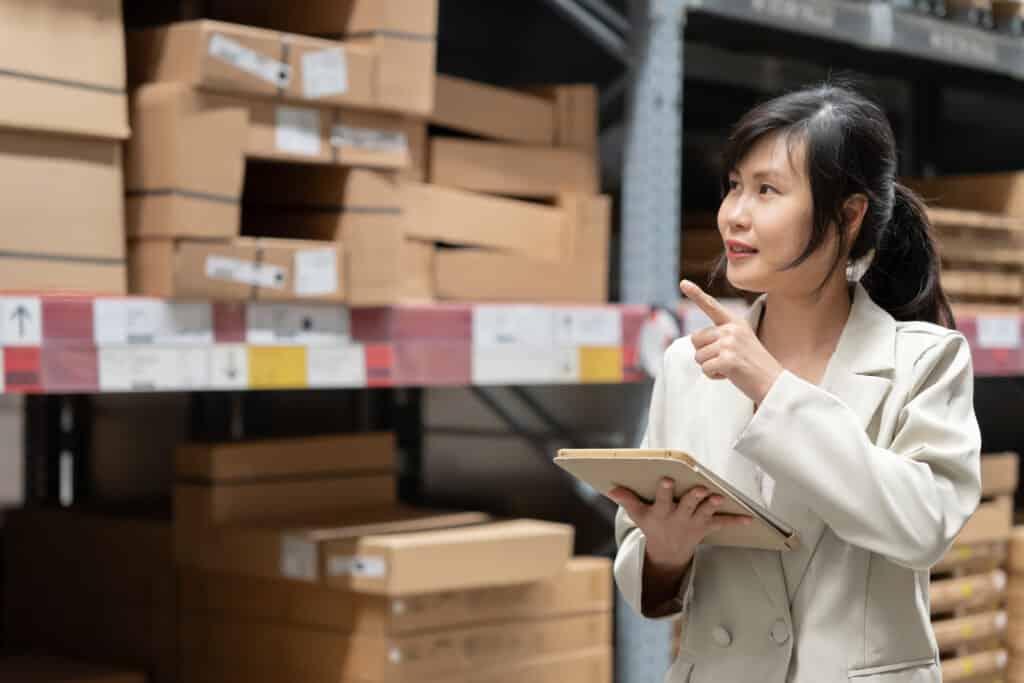 business woman using digital tablet checking amount of stock product inventory on shelf at distribution warehouse factory.logistic business shipping and delivery.